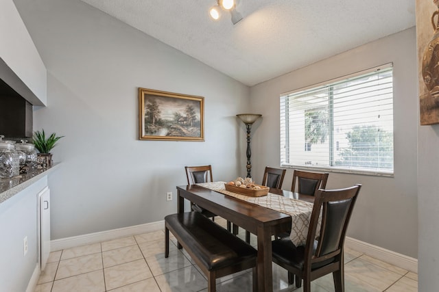 dining space featuring light tile patterned floors, a textured ceiling, and vaulted ceiling