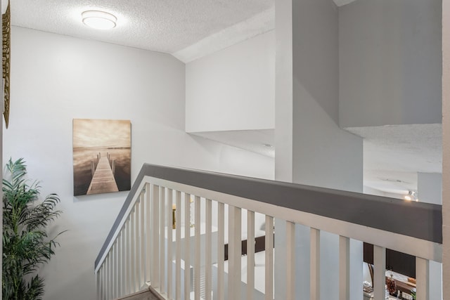 hall with vaulted ceiling and a textured ceiling