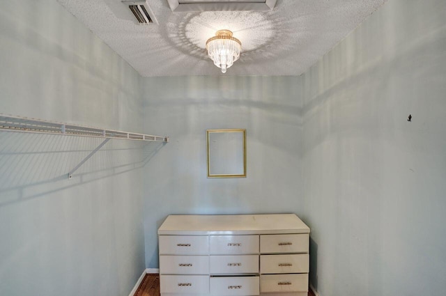 walk in closet featuring wood-type flooring and an inviting chandelier