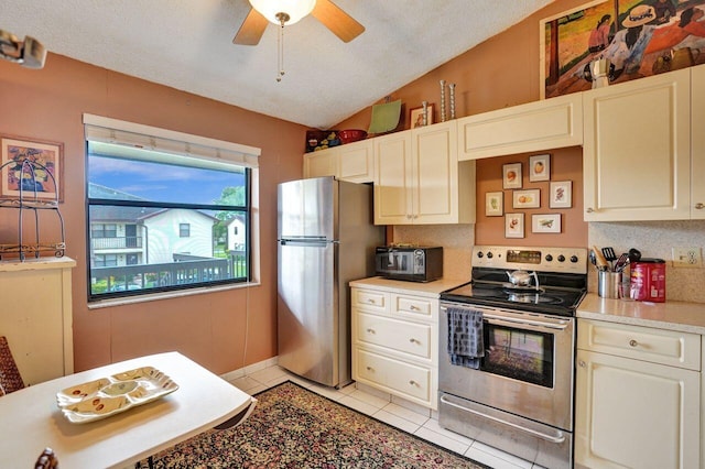 kitchen with ceiling fan, stainless steel appliances, backsplash, vaulted ceiling, and light tile patterned flooring