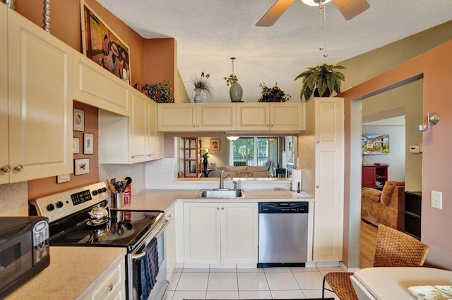 kitchen with light tile patterned floors, stainless steel appliances, light countertops, a ceiling fan, and a sink