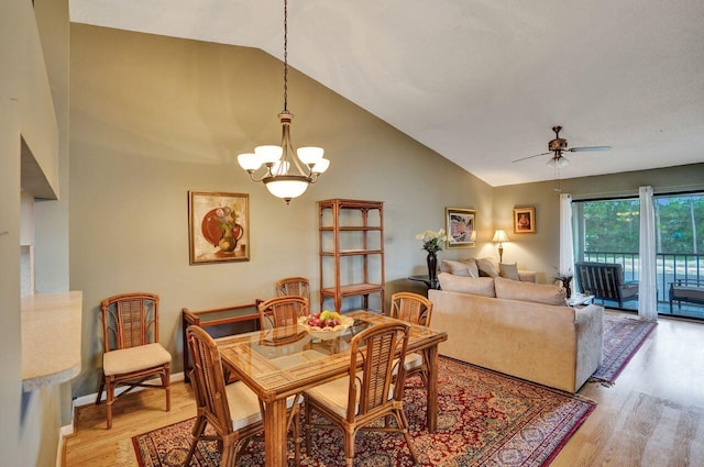 dining space featuring high vaulted ceiling, light wood-type flooring, baseboards, and ceiling fan with notable chandelier