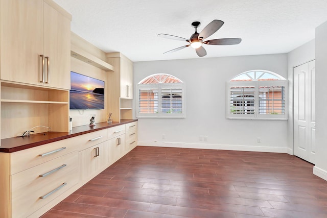 unfurnished living room featuring dark wood-type flooring, a textured ceiling, and ceiling fan