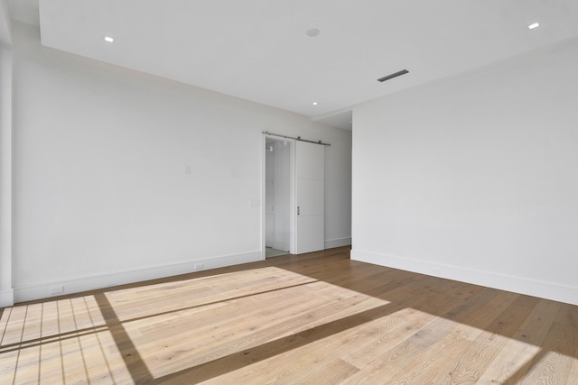 empty room with hardwood / wood-style flooring and a barn door