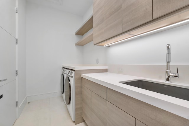 laundry area featuring washing machine and dryer, sink, and cabinets