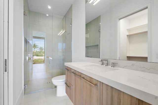 bathroom featuring toilet, vanity, tile patterned flooring, and an enclosed shower