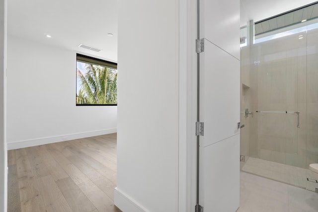 bathroom with hardwood / wood-style flooring and a shower with shower door