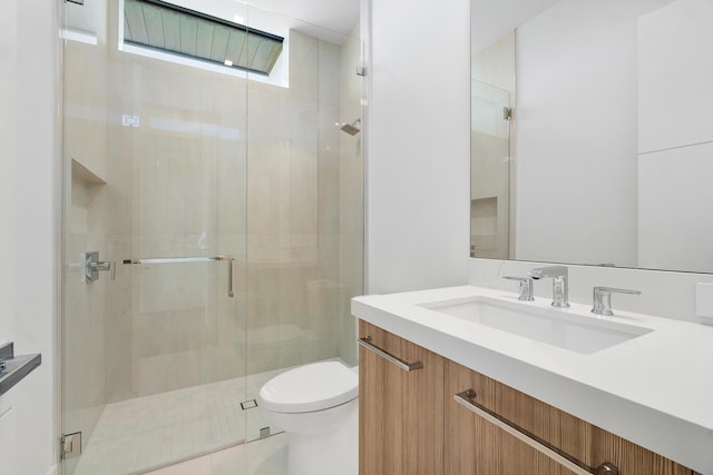 bathroom with toilet, vanity, and a shower with door