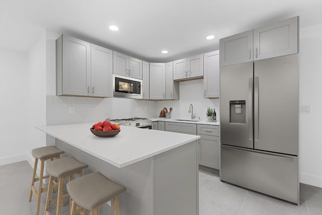 kitchen featuring stainless steel fridge, a kitchen breakfast bar, black microwave, and gray cabinets