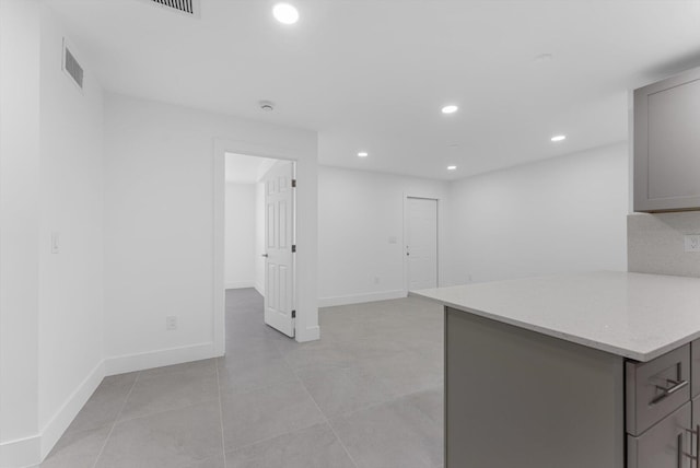 kitchen with gray cabinetry, light stone counters, and light tile patterned flooring