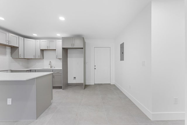 kitchen featuring sink, light tile patterned floors, electric panel, gray cabinets, and backsplash