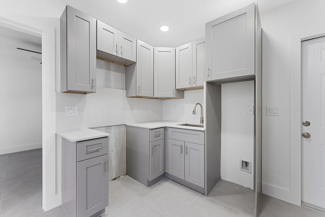 kitchen featuring gray cabinetry, sink, backsplash, and light tile patterned flooring