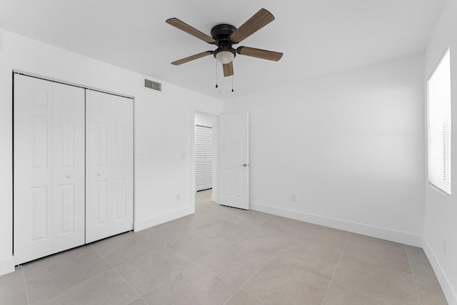 unfurnished bedroom with light tile patterned flooring, ceiling fan, and a closet