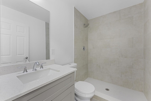 bathroom with tiled shower, vanity, and toilet