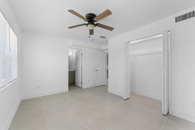 unfurnished bedroom featuring multiple windows, ensuite bathroom, ceiling fan, and a closet