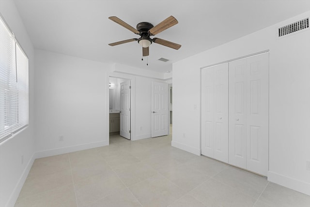 unfurnished bedroom with light tile patterned flooring, ceiling fan, ensuite bath, and a closet