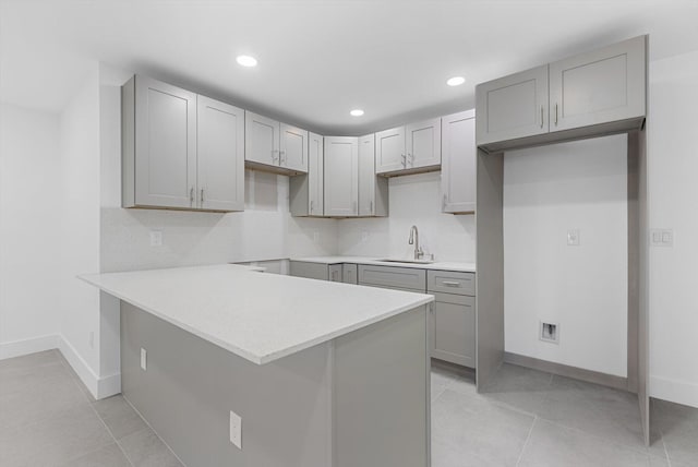 kitchen with backsplash, sink, and gray cabinetry