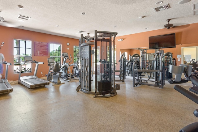 exercise room with visible vents, a textured ceiling, and baseboards