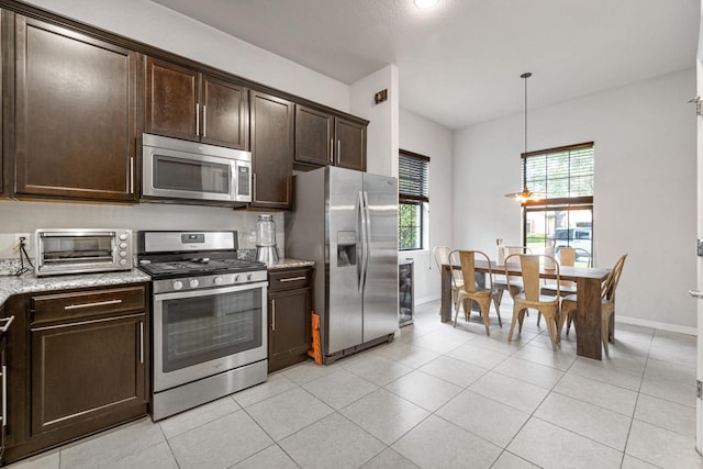 kitchen featuring light stone counters, stainless steel appliances, dark brown cabinetry, and a toaster