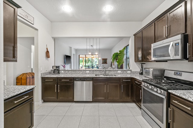 kitchen featuring dark brown cabinetry, a toaster, light stone counters, appliances with stainless steel finishes, and a sink