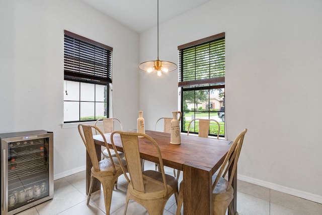 dining space with light tile patterned flooring, beverage cooler, baseboards, and a wealth of natural light