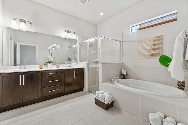 bathroom with a garden tub, double vanity, a stall shower, tile patterned floors, and a sink