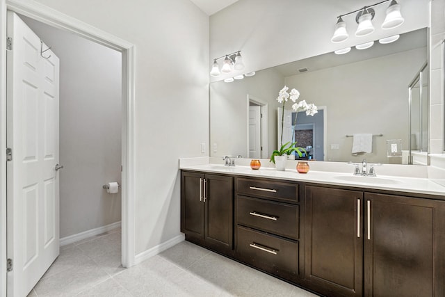 bathroom with a sink, baseboards, double vanity, and tile patterned floors