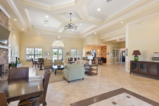 living room with a high ceiling, a stone fireplace, crown molding, baseboards, and a chandelier