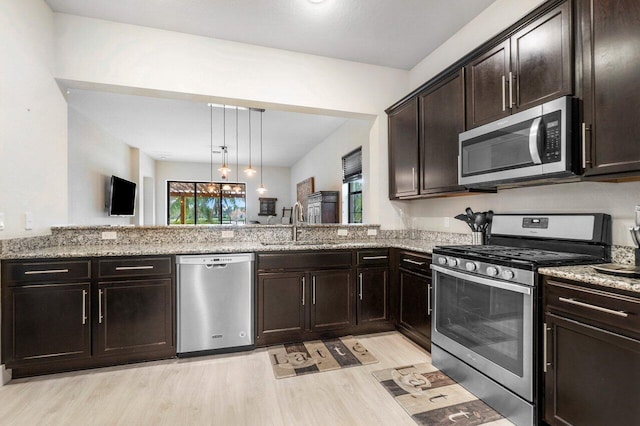 kitchen featuring a sink, stainless steel appliances, plenty of natural light, and light stone countertops