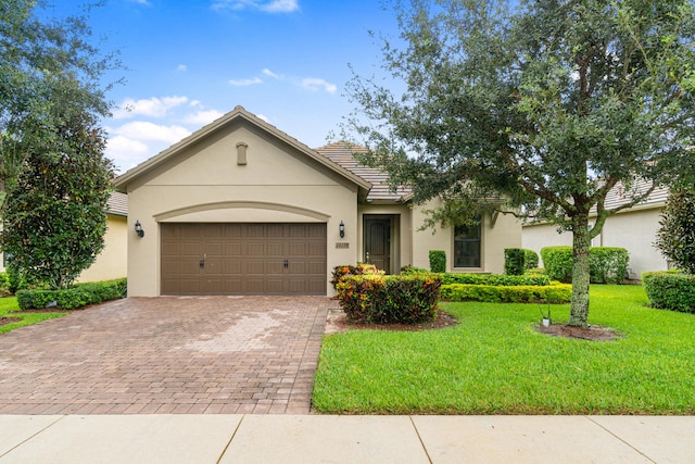 ranch-style home featuring a tile roof, decorative driveway, an attached garage, and stucco siding