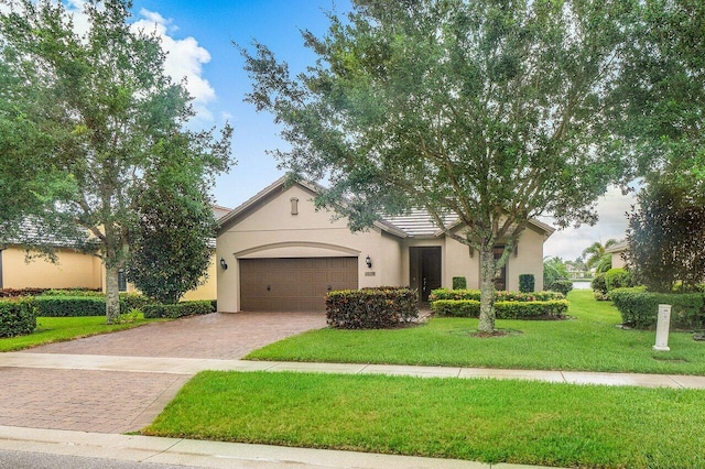 view of front of property featuring stucco siding, an attached garage, decorative driveway, and a front lawn