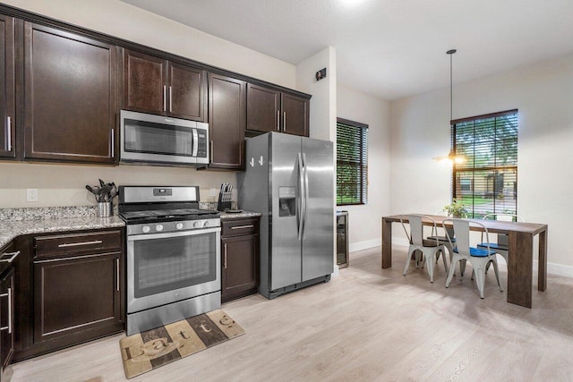 kitchen with light stone counters, light wood-style flooring, dark brown cabinets, and stainless steel appliances