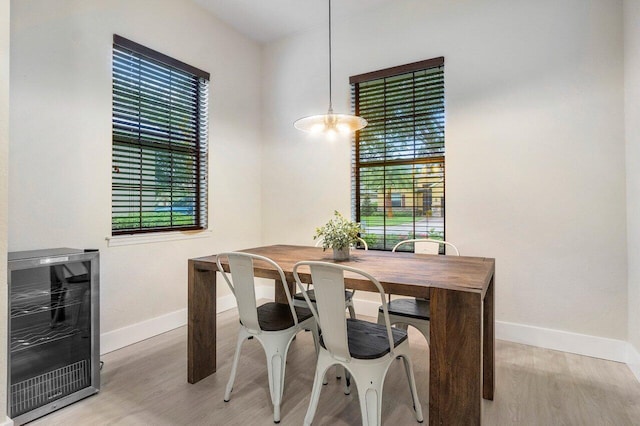 office space with baseboards, wine cooler, a healthy amount of sunlight, and light wood finished floors