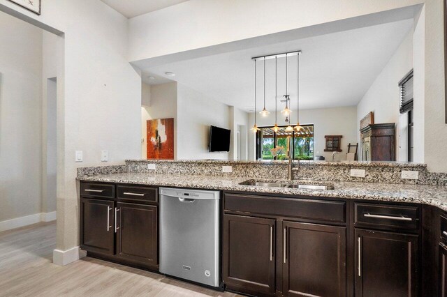 kitchen with light stone counters, a peninsula, a sink, dark brown cabinetry, and dishwasher