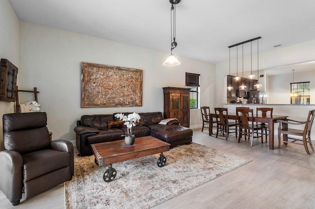 living room featuring baseboards, visible vents, and light wood finished floors