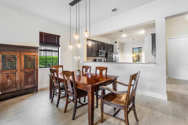 dining space featuring visible vents, baseboards, and light wood-style flooring