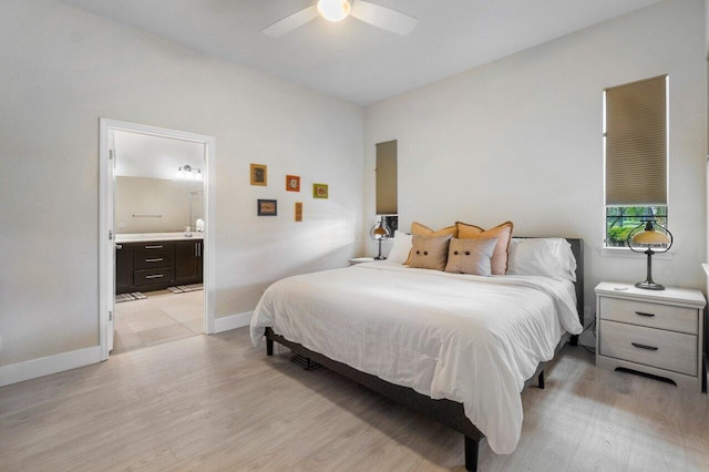 bedroom featuring light wood finished floors, connected bathroom, a ceiling fan, and baseboards