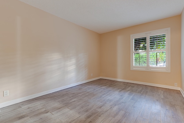 unfurnished room featuring light hardwood / wood-style flooring and a textured ceiling