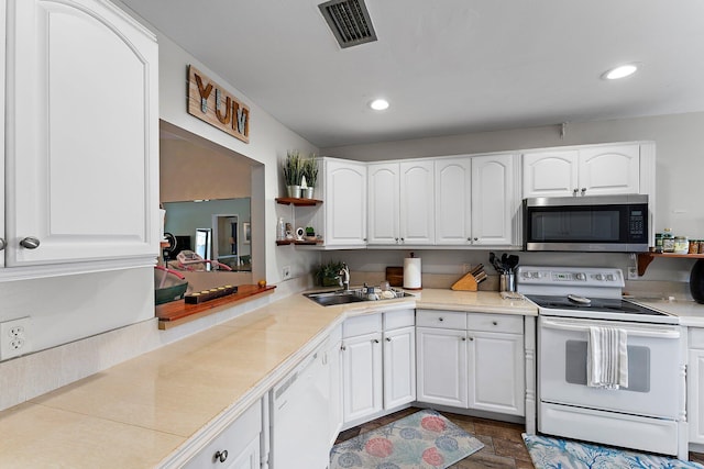 kitchen featuring sink, white appliances, and white cabinetry