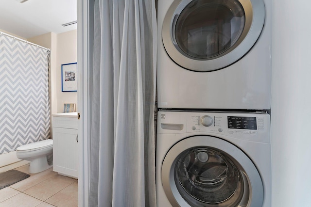 laundry area with stacked washer and dryer and light tile patterned flooring