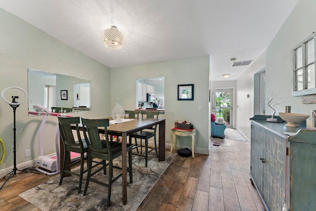 dining room with wood-type flooring and vaulted ceiling