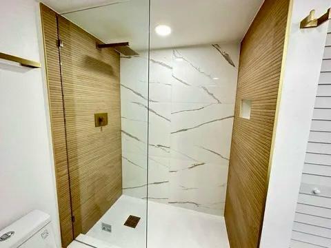 bathroom with a tile shower and toilet