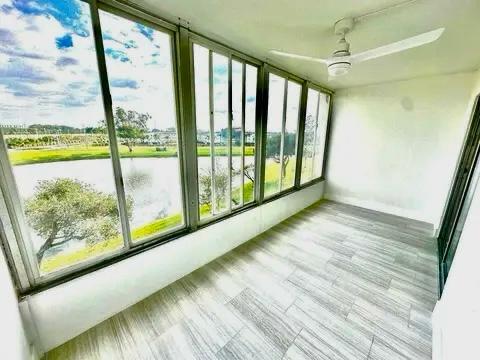 unfurnished sunroom featuring ceiling fan and a water view