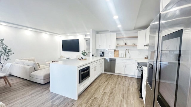 kitchen with backsplash, kitchen peninsula, light hardwood / wood-style flooring, appliances with stainless steel finishes, and white cabinetry