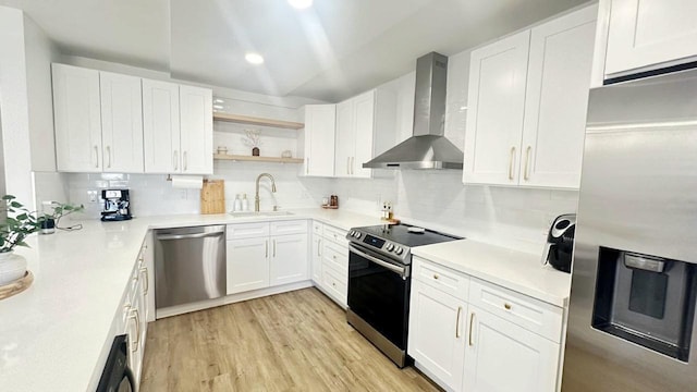 kitchen with stainless steel appliances, white cabinetry, wall chimney exhaust hood, and sink