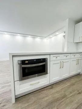 kitchen with white cabinets, oven, and light hardwood / wood-style floors