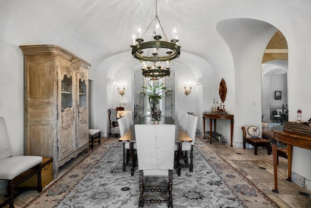 dining space with lofted ceiling, a notable chandelier, and arched walkways