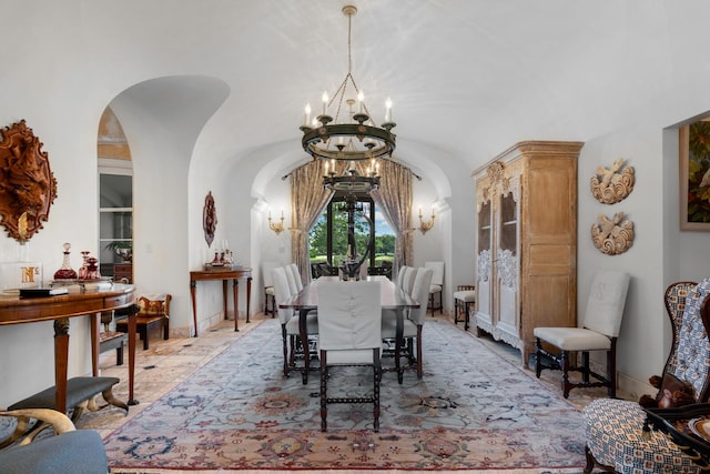 dining area with vaulted ceiling, baseboards, arched walkways, and a chandelier