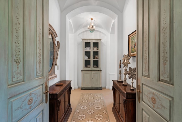 carpeted entryway with vaulted ceiling and an inviting chandelier