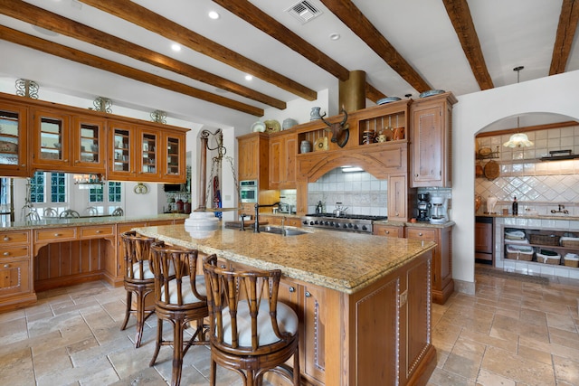 kitchen featuring beamed ceiling, an island with sink, tasteful backsplash, and pendant lighting